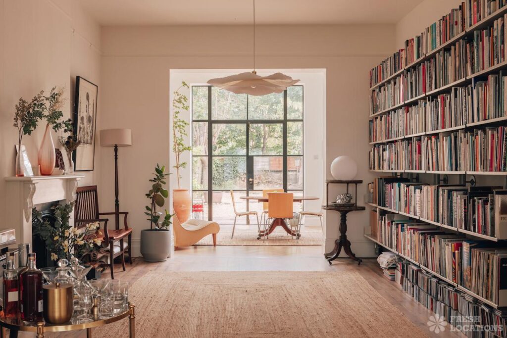 Perfect shoot location for your brand campaign in london: bright home library living room with floor-to-ceiling bookshelves and large glass doors to a garden.